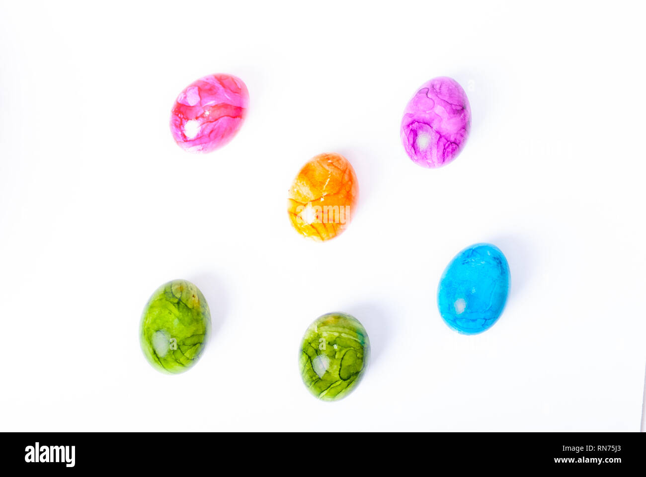 Flat lay of colorful painted easter eggs laying on white background ...