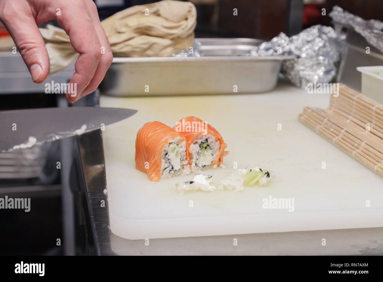 https://c8.alamy.com/comp/RN7AXM/closeup-of-the-hand-the-cook-cuts-a-philadelphia-roll-in-a-restaurant-kitchen-with-a-sharp-knife-of-sushi-concept-cooking-japanese-dishes-RN7AXM.jpg