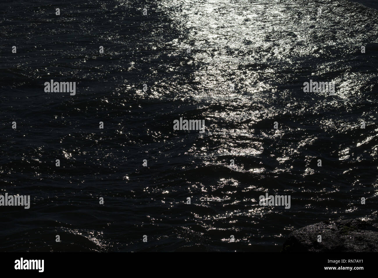 Sea water slowly waves under the last sun light producing beautiful patterns. Stock Photo