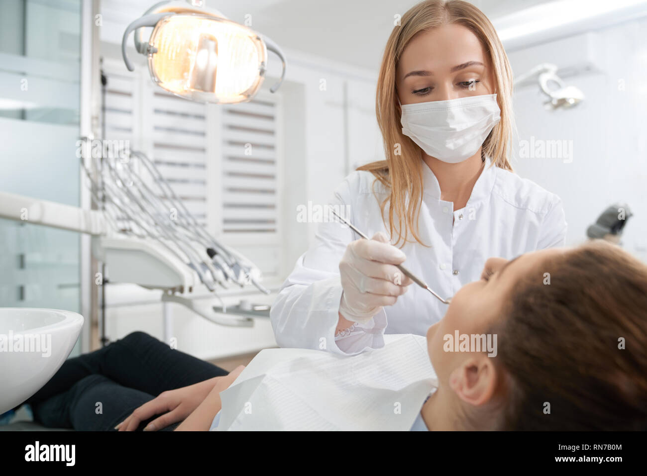 Professional dentist wearing medical mask, gloves and white uniform