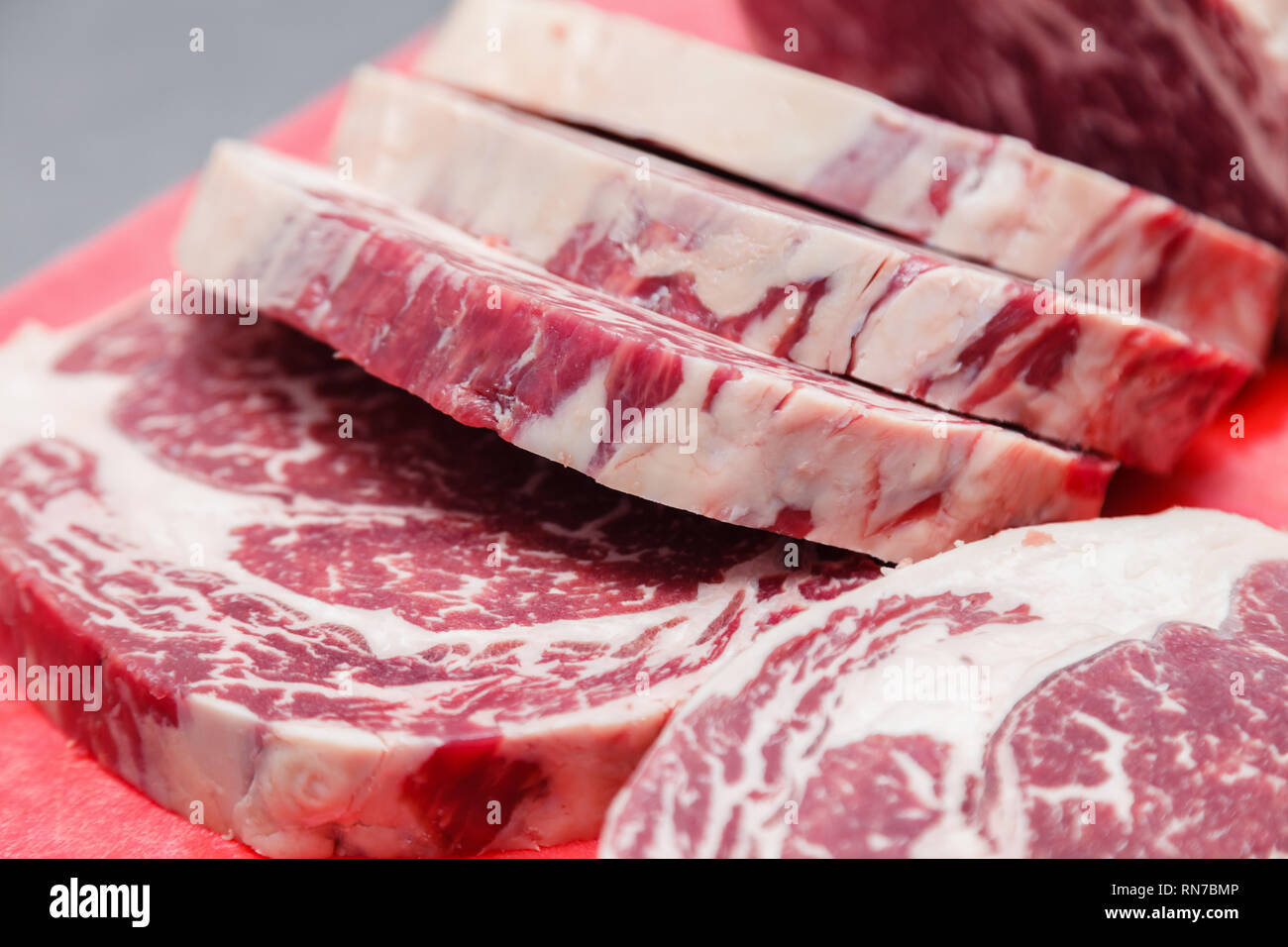 Closeup macro pieces ribeye marbled beef steak on red plastic cutting