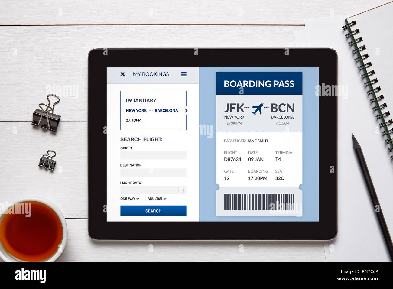 Boarding pass concept on tablet screen with office objects on white wooden table. All screen content is designed by me. Flat lay Stock Photo