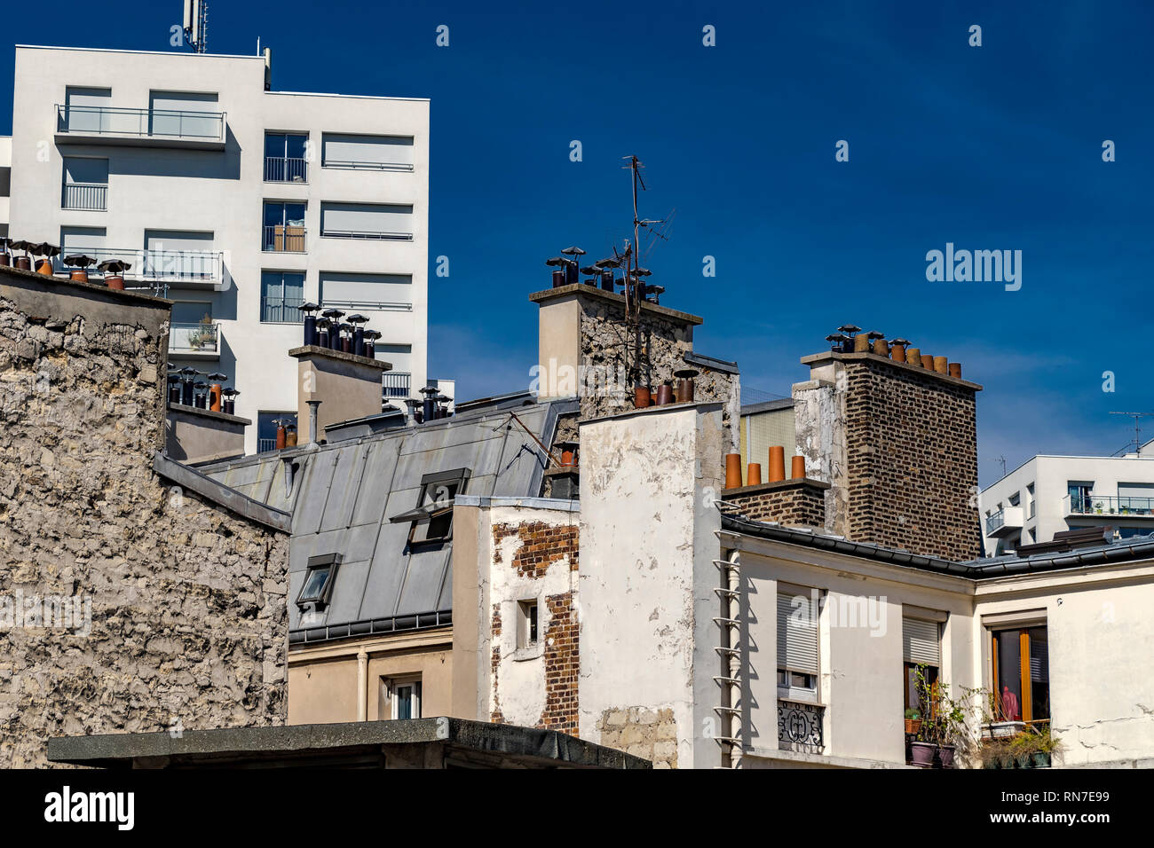 Paris building with attic rooms, tall chimney stacks and grey slate roof tiles  , Paris, France Stock Photo