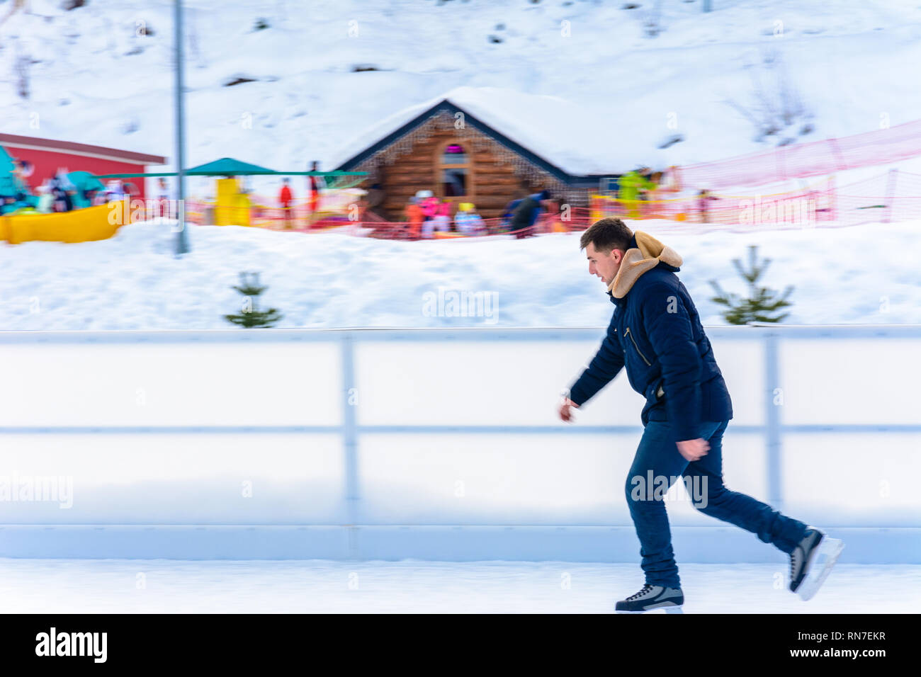 A beginner man rides a skating rink in an open-air ski resort 2019 ...