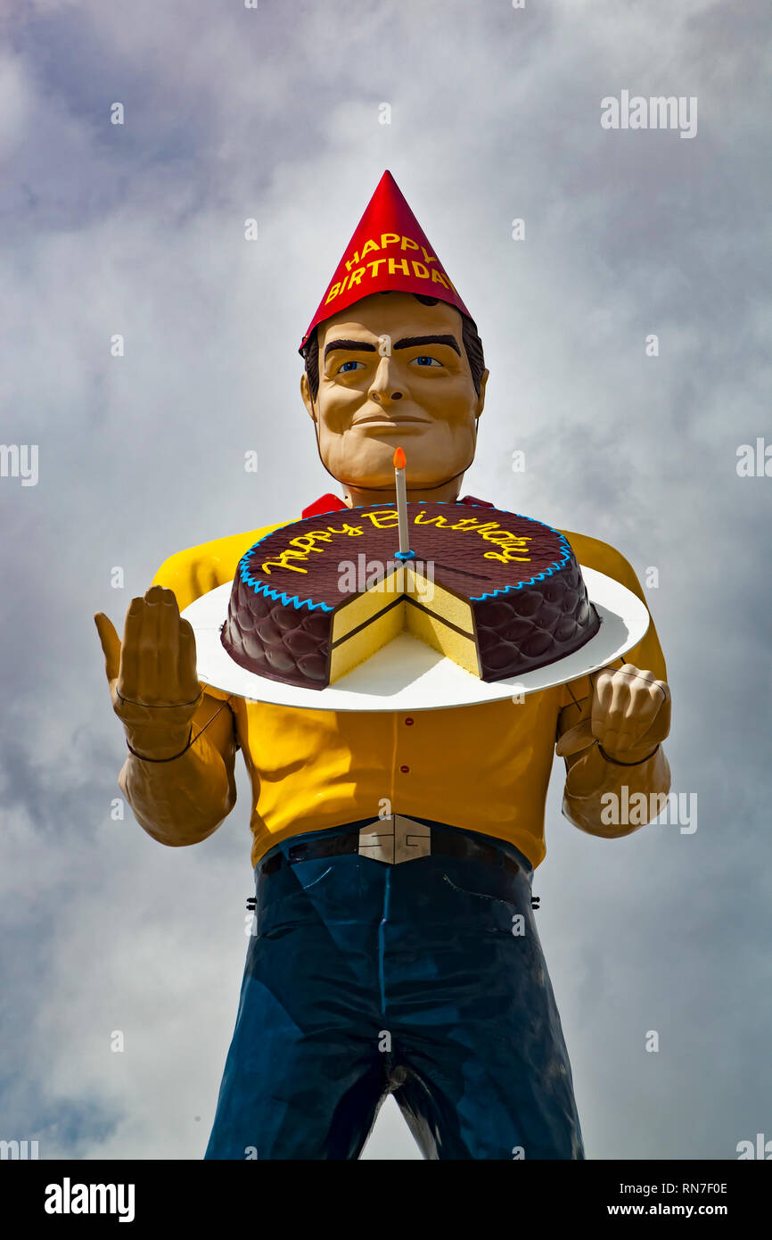 'Sunny' the Big Man muffler man dressed with birthday hat and holding a birthday cake, located at Sun Glass, Farmington, New Mexico USA Stock Photo