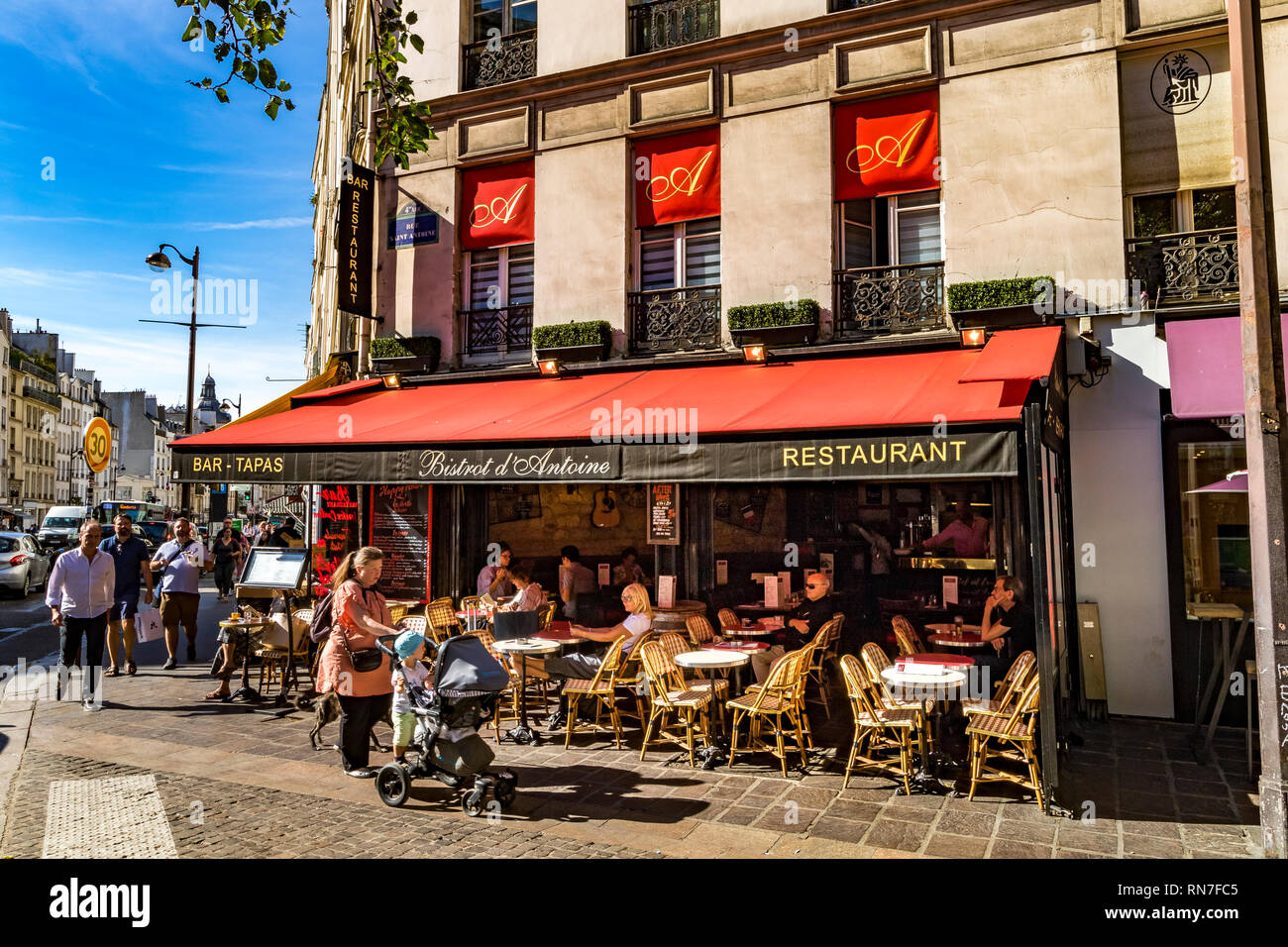 A woman with a young child and pushing a buggy walk past  Le Bistrot D'Antoine on rue Saint Antoine in the Le Marais district ,Paris ,France Stock Photo