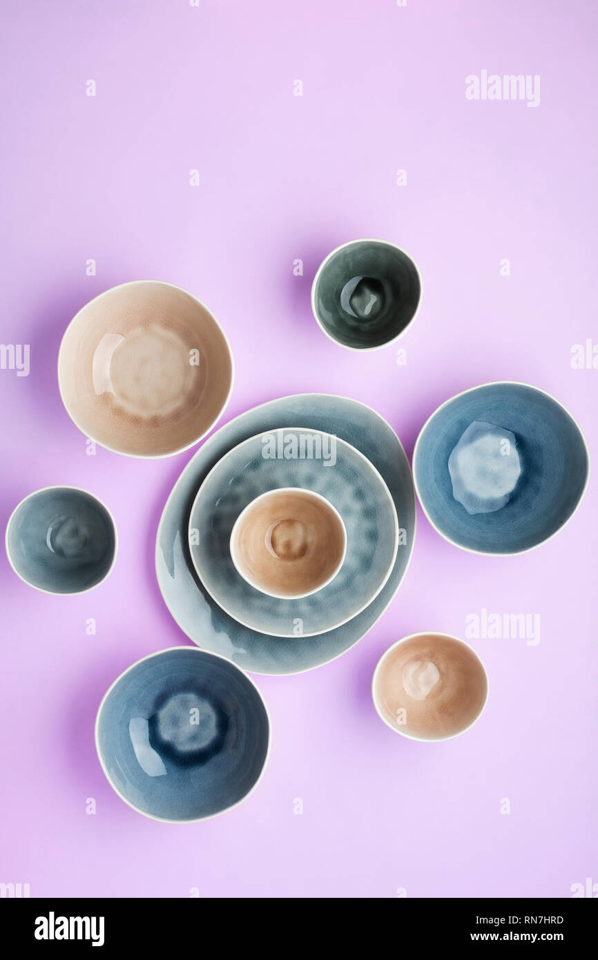 Beautiful blue, grey, beige dinnerware, plates bowls on lilac table, top view, selective focus Stock Photo