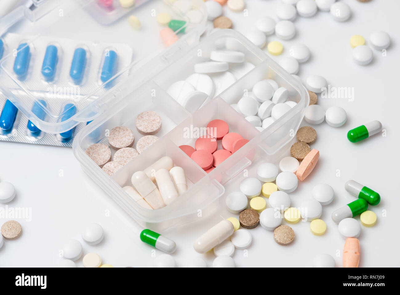 Close-up of pill case with various colorful medications on white background. Stock Photo