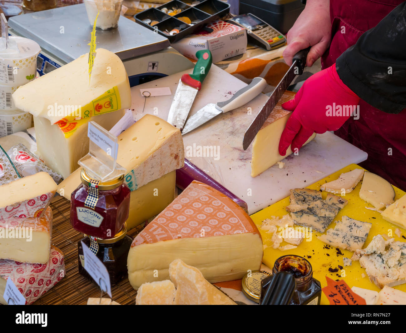 Woman cutting cheese, cheese stall, Leith Saturday market, Dock Place, Edinburgh, Scotland, UK Stock Photo
