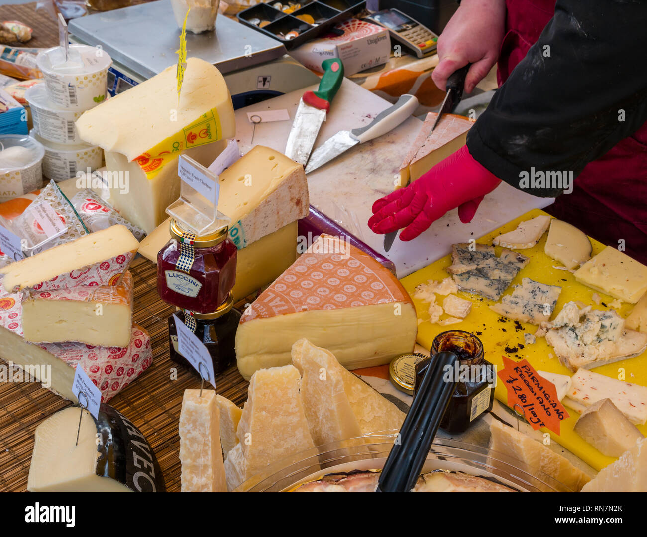 Woman cutting cheese, cheese stall, Leith Saturday market, Dock Place, Edinburgh, Scotland, UK Stock Photo