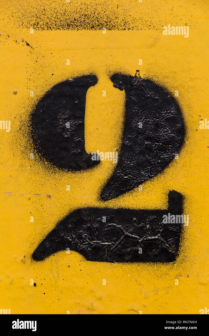 black number stencil painted on yellow background, number two, number 2