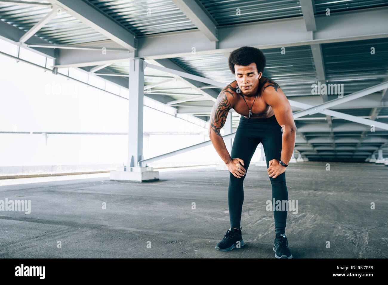 Muscular runner with eyes closed taking deep breath during intense training Stock Photo