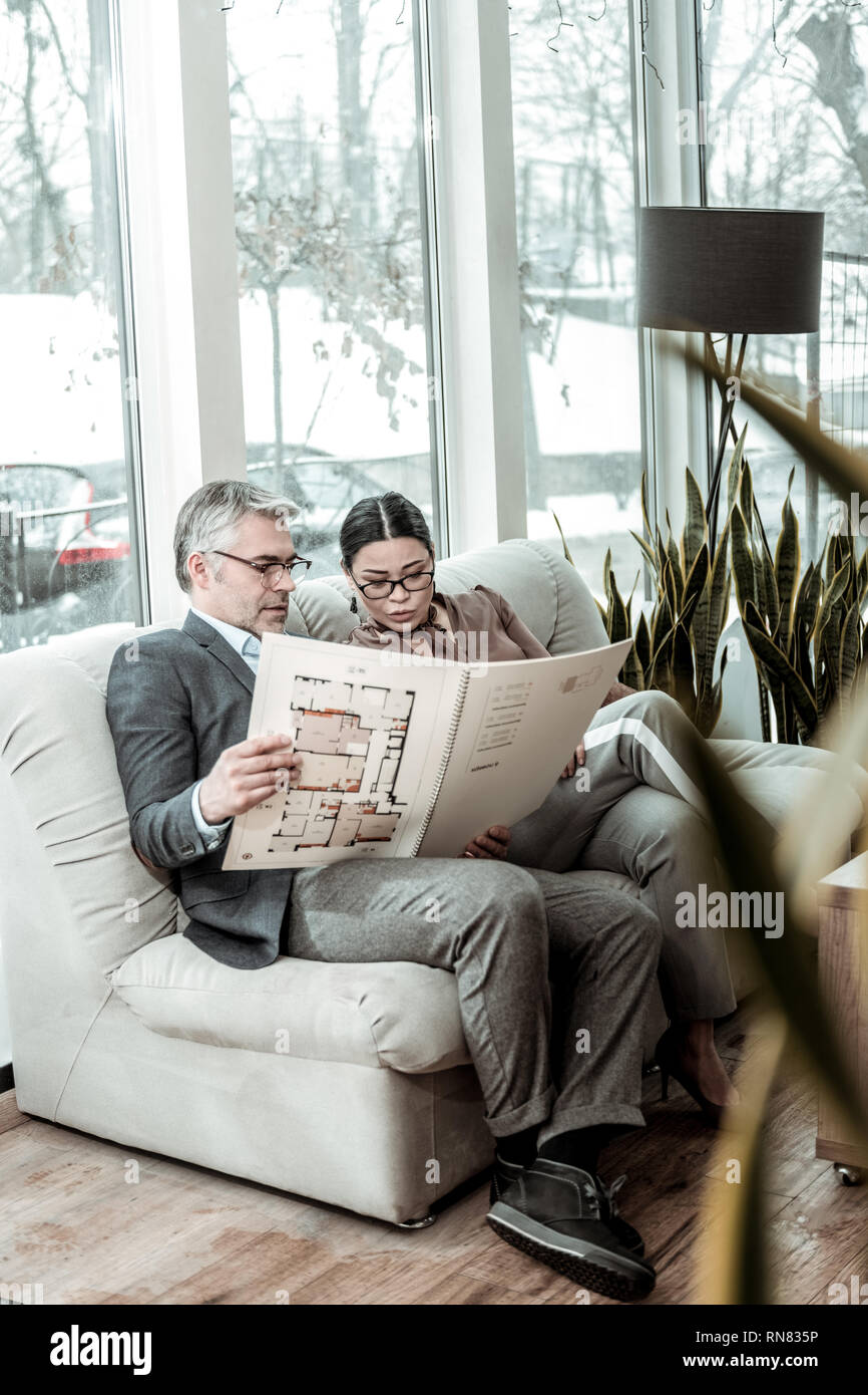 Brunette adult businesswoman in a brown satin blouse discussing new information with her partner Stock Photo