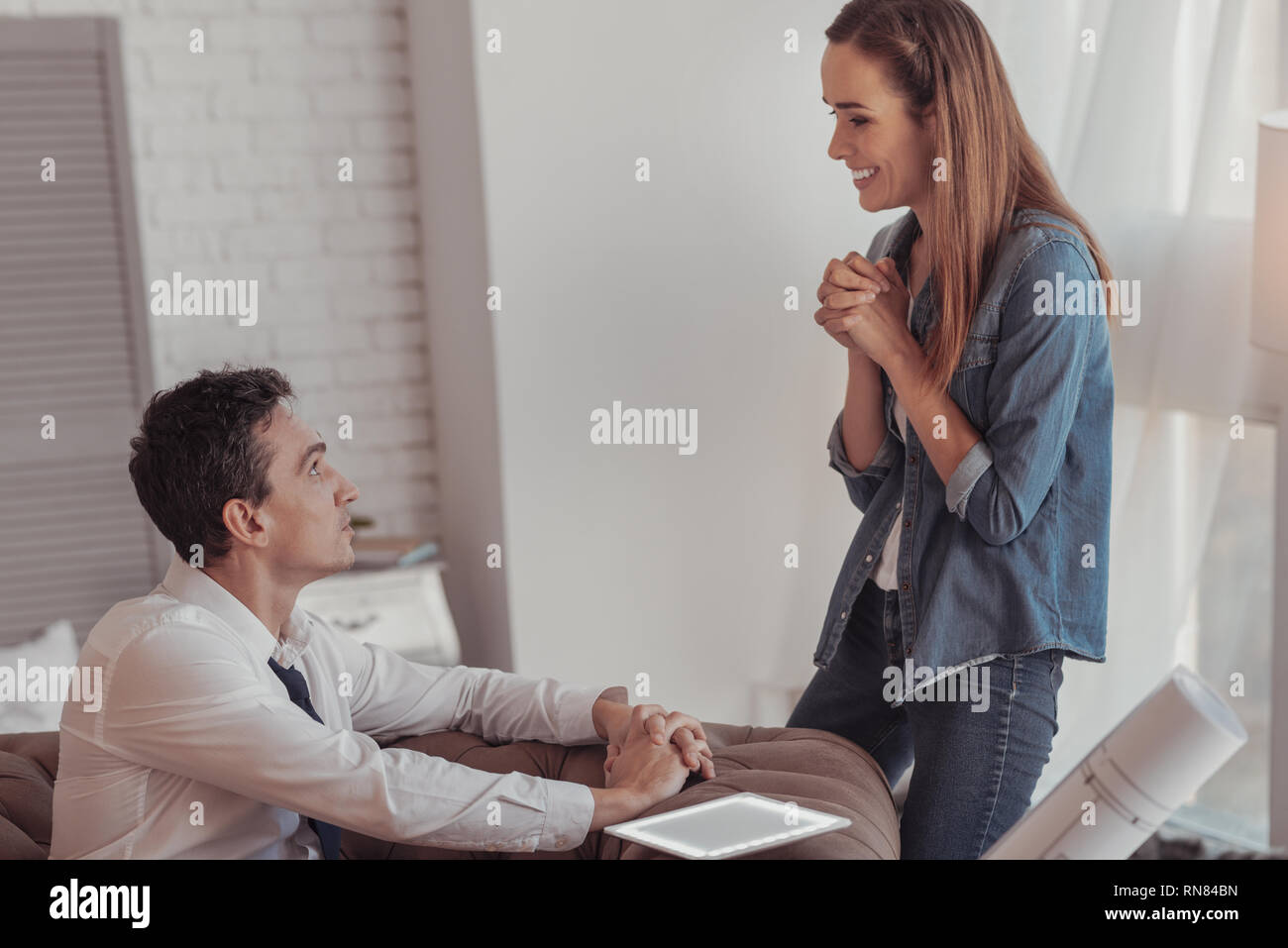 Let me go out today. Delighted gorgeous wife looking at her handsome husband and sweet talking him while keeping hands with fingers in crossed positio Stock Photo