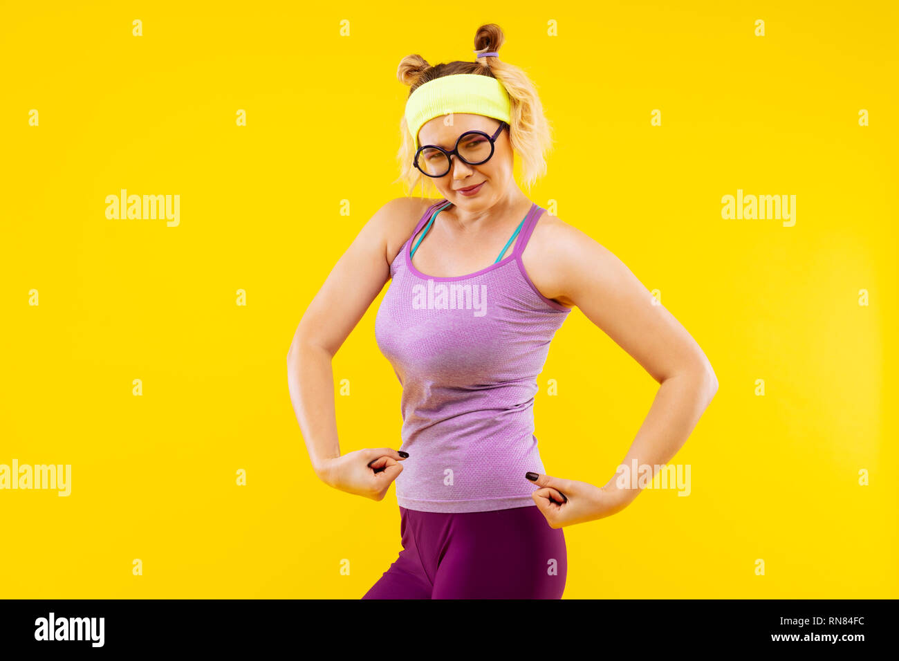 Woman wearing purple leggings and camisole showing strength Stock Photo