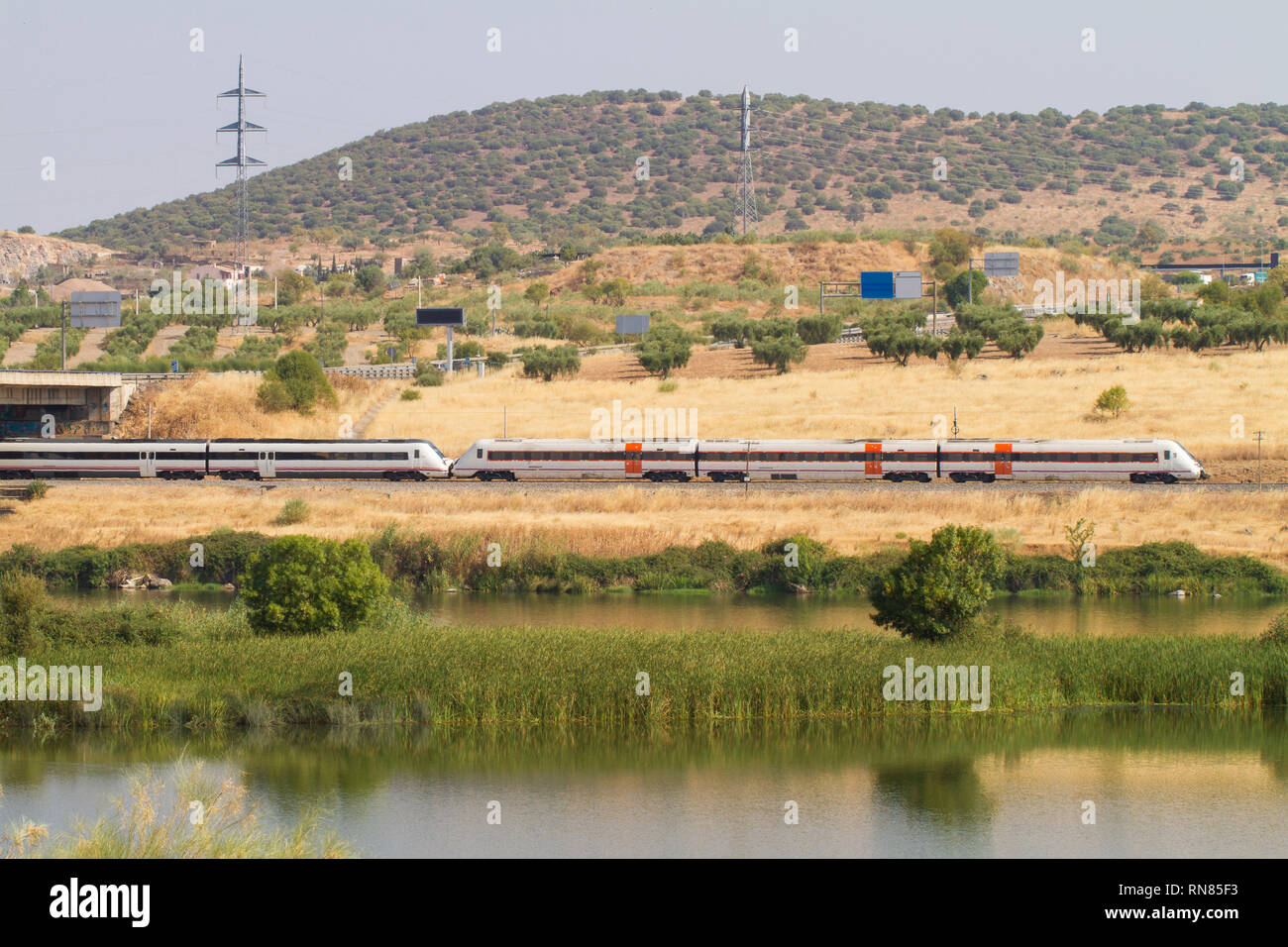 Automotive train of travelers, with diesel traction used as regional transport in Spain as it passes through Mérida with the Guadiana River in the for Stock Photo