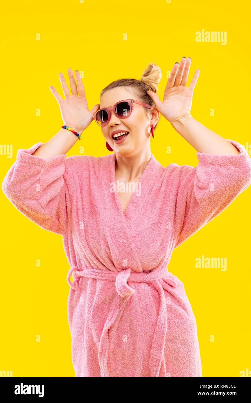 Funny woman wearing bright pink bathrobe making funny pose Stock Photo