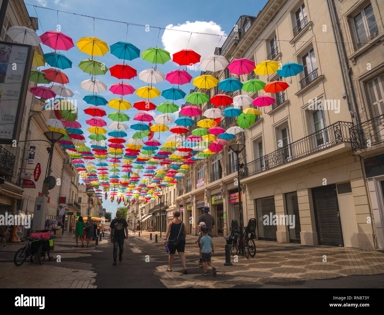 Rainbow/multi-coloured umbrellas hanging over a cobbled street in Saumur, Loire Valley, France. Stock Photo