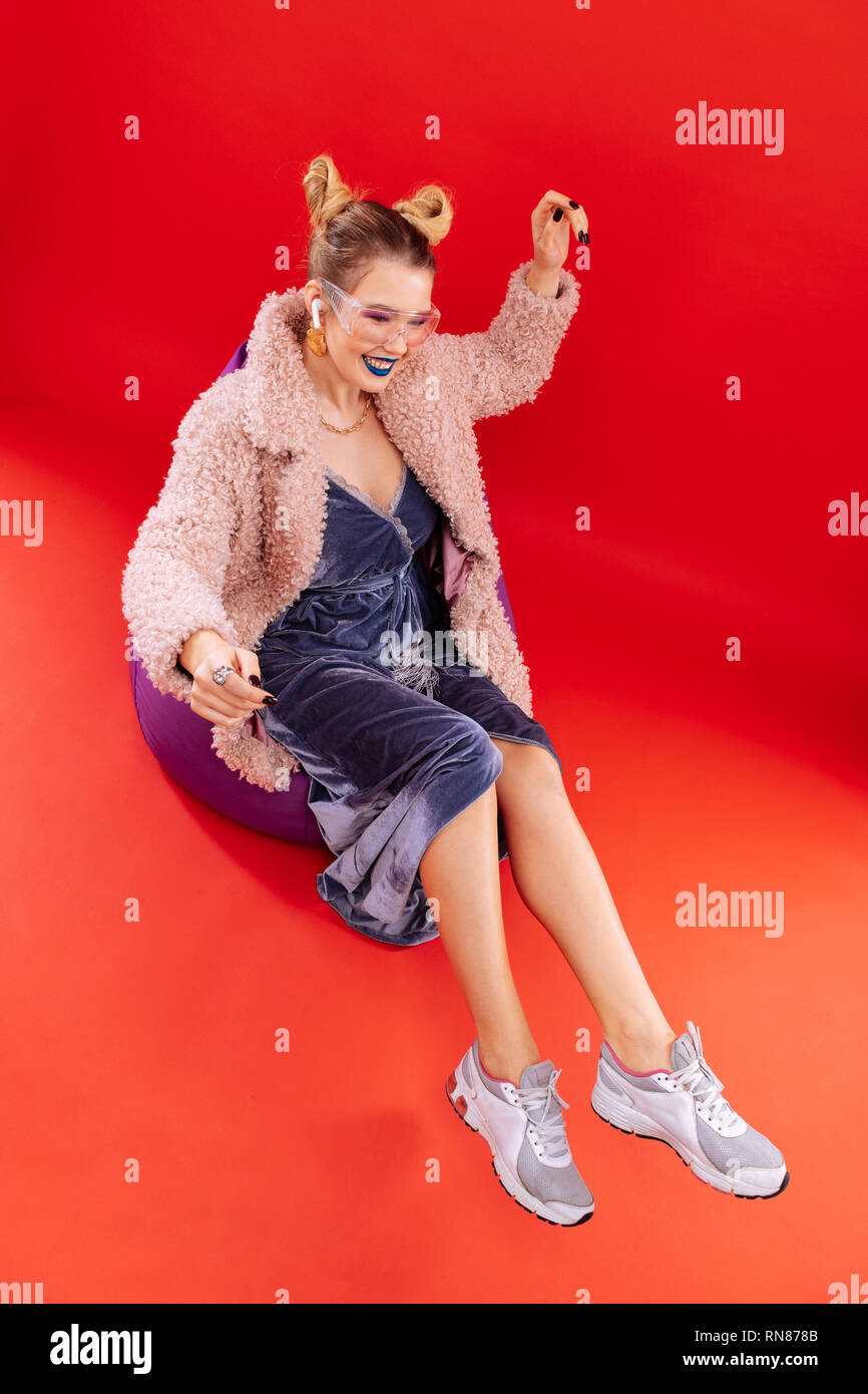 Fashionable woman wearing grey sneakers sitting on comfy chair Stock Photo