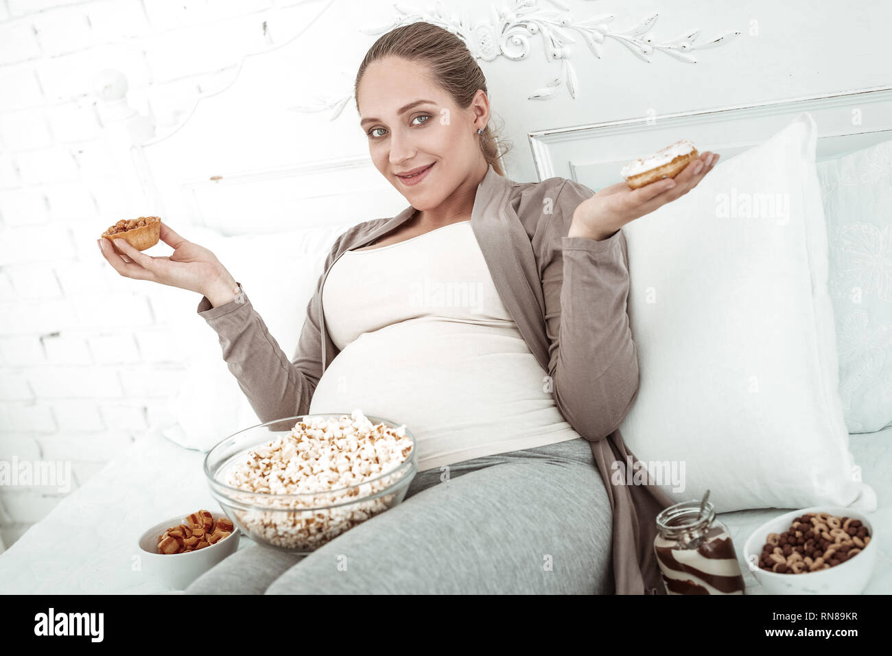 Beaming coquettish future mother with round belly spreading hands Stock Photo