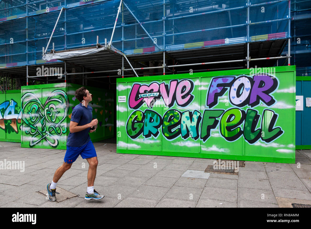 Man jogging past a Love for Grenfell sign at Trellick Tower, Notting Hill, London, England, United Kingdom Stock Photo