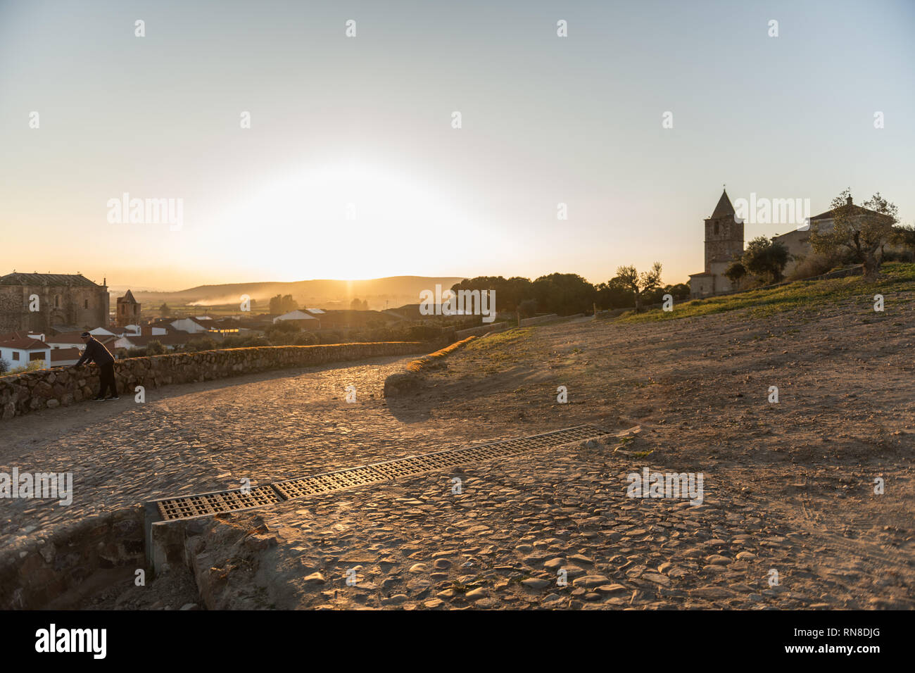 An older man contemplates the sunset over the village in Medellin, Extremadura, Spain. Stock Photo