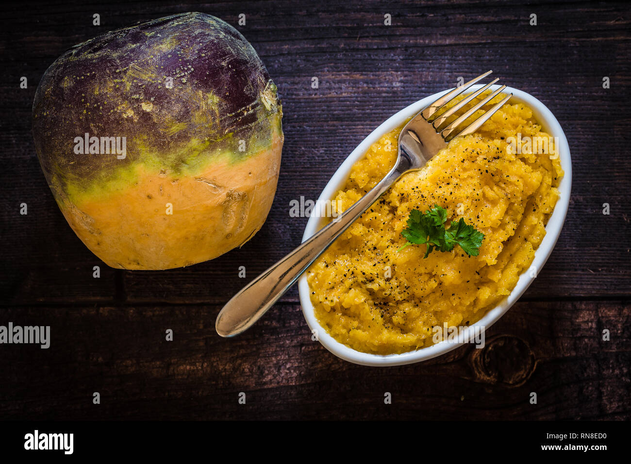 Healthy root vegetable Swede whole, with a bowl of Swede cooked and mashed in a white bowl. This vegetable is high in fibre. Stock Photo