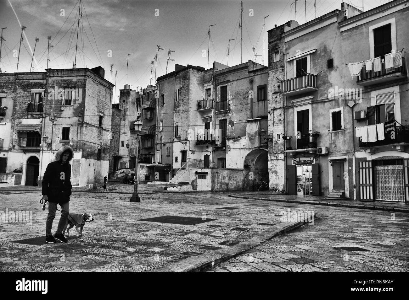 BARI, ITALY - FEBRUARY 8, 2019. Night cityscape  in the Old Town , historical center of Bari , Italy. Man and dog passing. Black and white image. Stock Photo