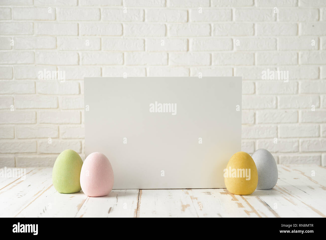 Easter composition with eggs, white board against white bricks wall Stock Photo