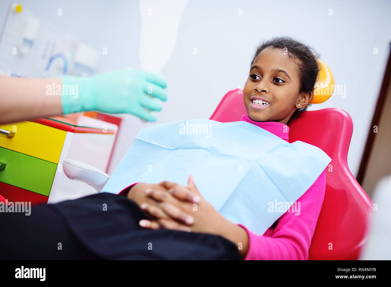 African American baby girl smiling sitting in a dental chair Stock Photo