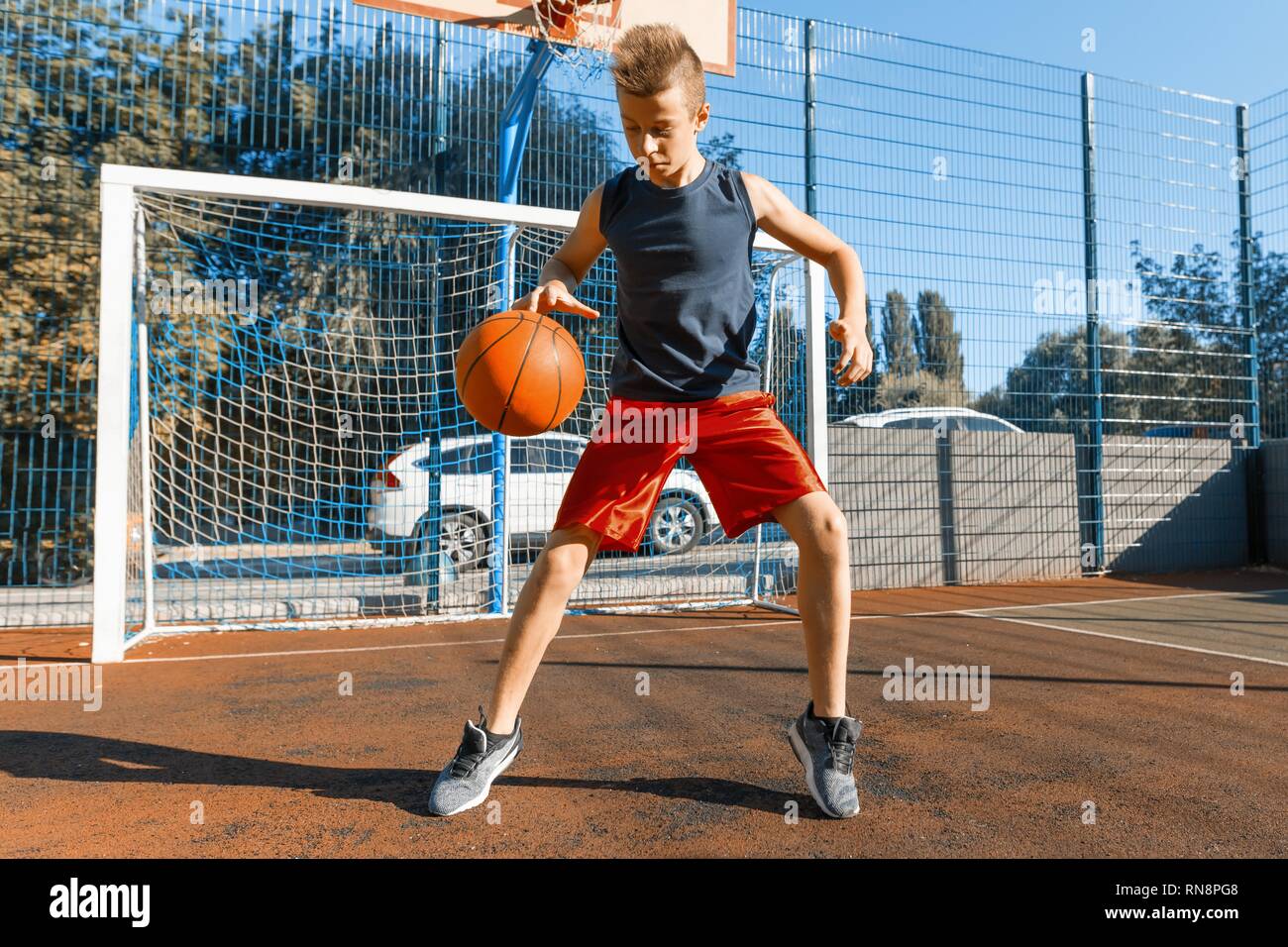 Caucasian teenager boy street basketball player with ball on outdoor
