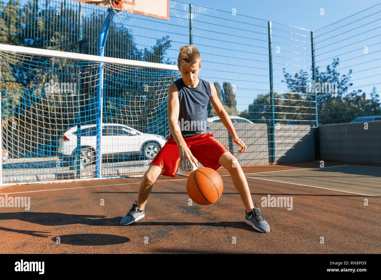 Caucasian teenager boy street basketball player with ball on outdoor