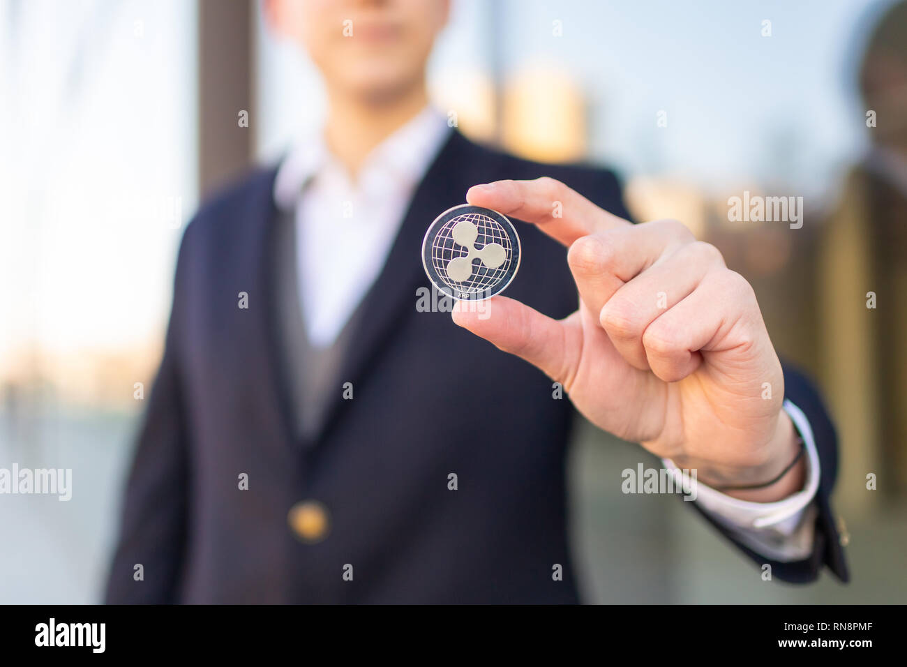 Ripple cryptocurrency coin in a young businessman hand. Disruptive  blockchain technology concept and transfer of wealth Stock Photo - Alamy