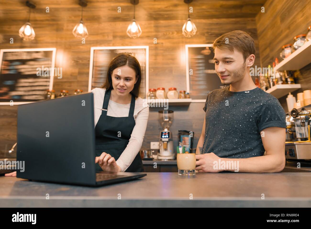 Team of coffee shop workers working near the counter with laptop