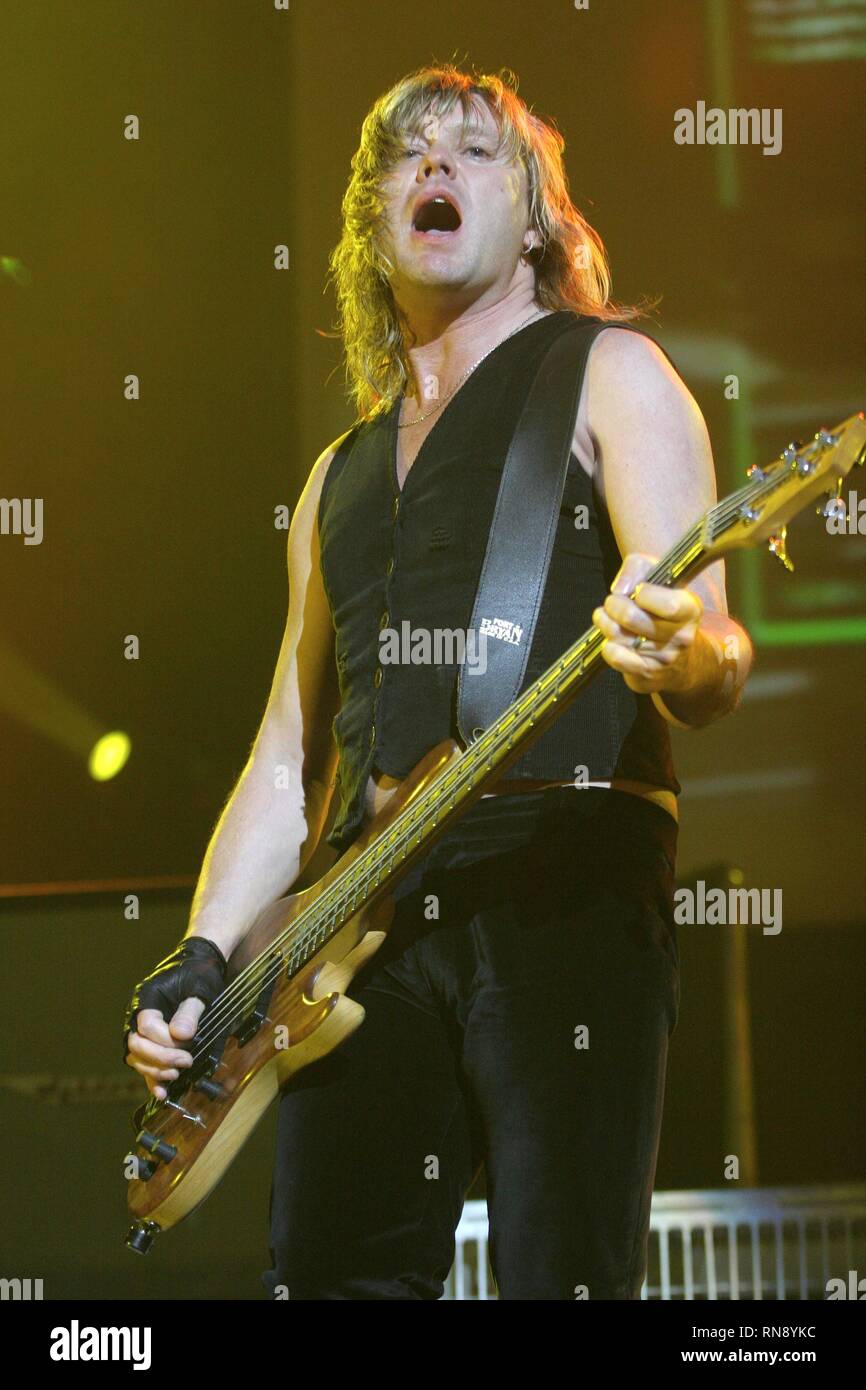 Def Leppard bassist Rick Savage is shown performing on stage during a concert appearance. Stock Photo