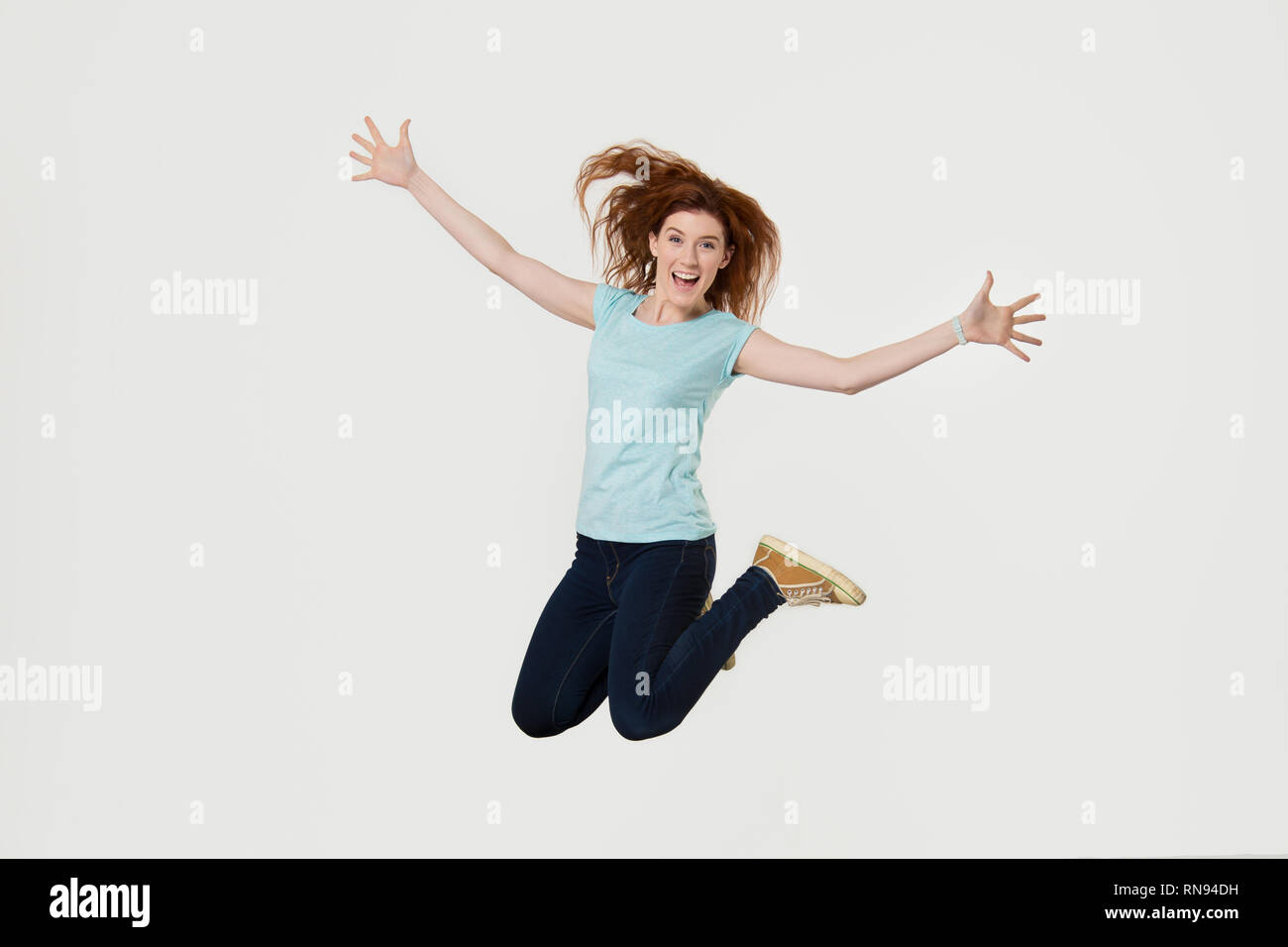 Happy active young woman jumping in air screaming with joy Stock Photo
