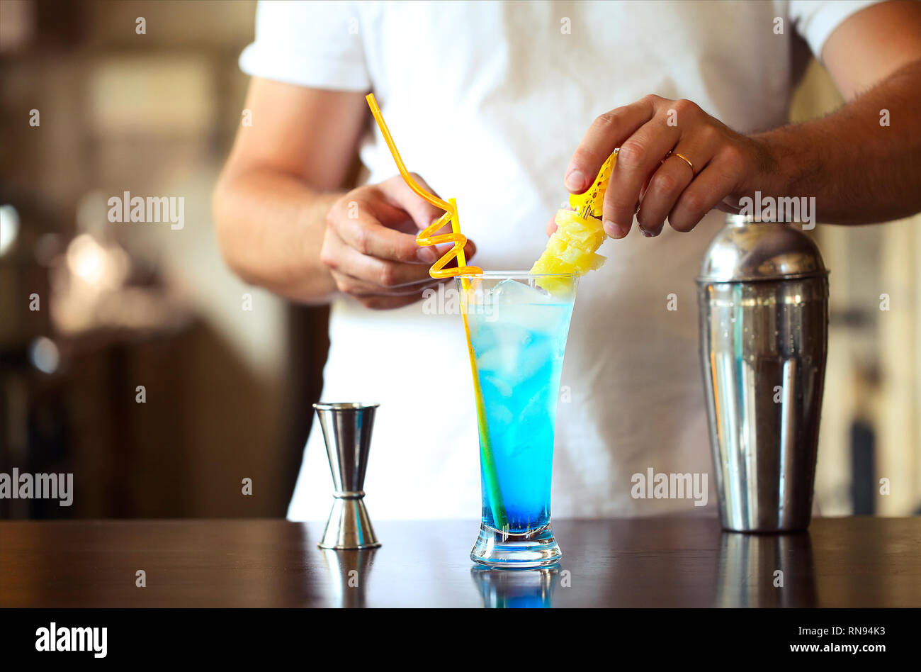 Barman at work, preparing cocktails. Pouring blue lagoon cocktail glass