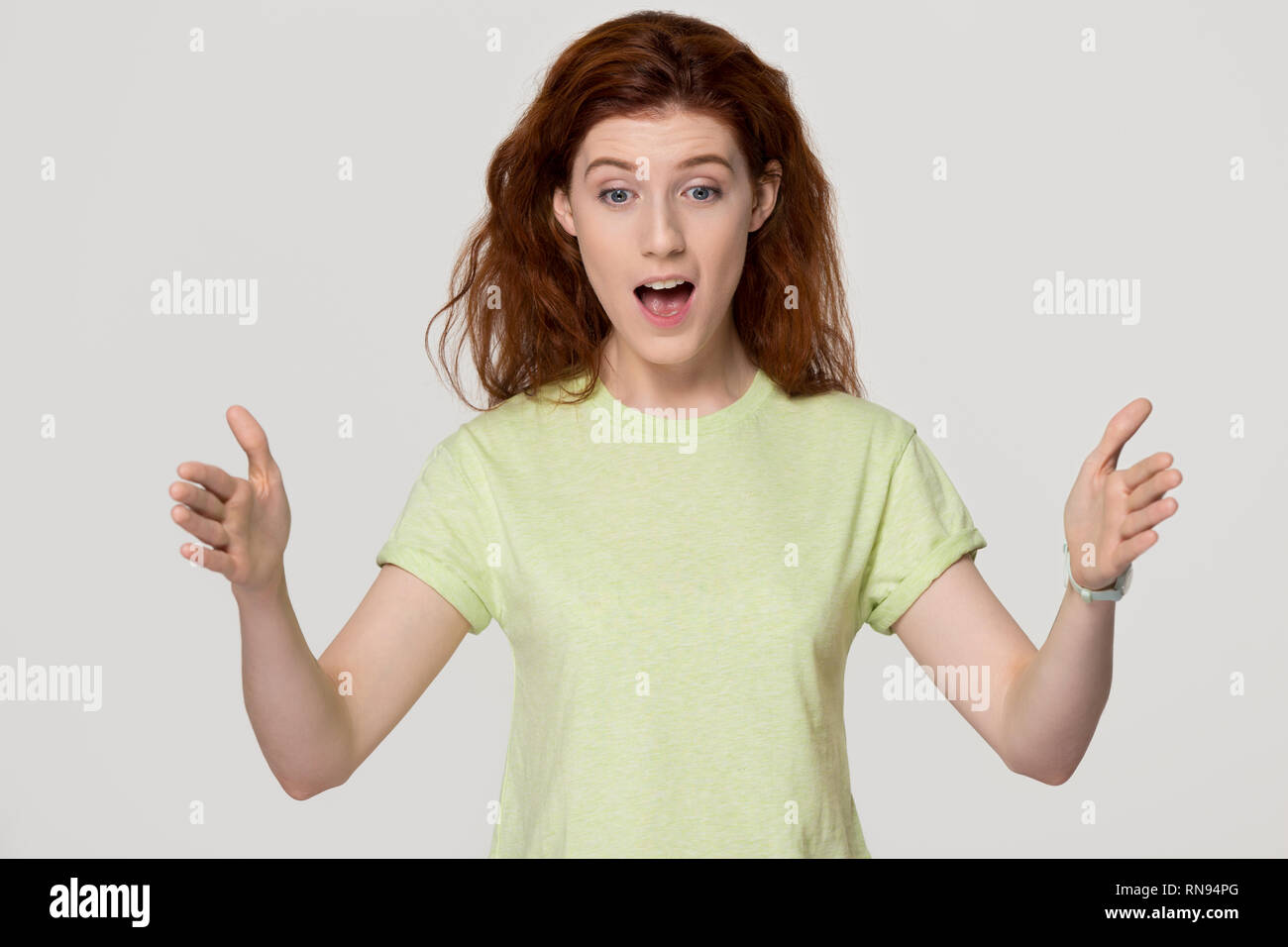 Shocked amazed redhead woman showing something big looking at hands Stock Photo