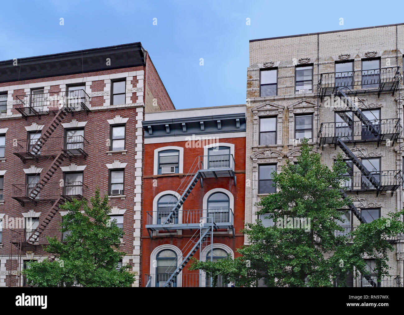 old New York apartment building with external fire escapes, window air conditioners, and ornate trim around windows Stock Photo