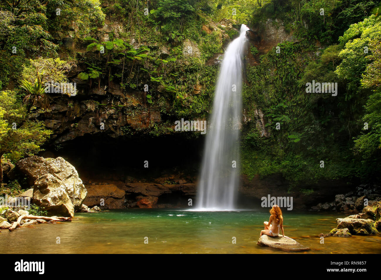 Young woman in bikini sitting by Lower Tavoro Waterfalls in Bouma ...