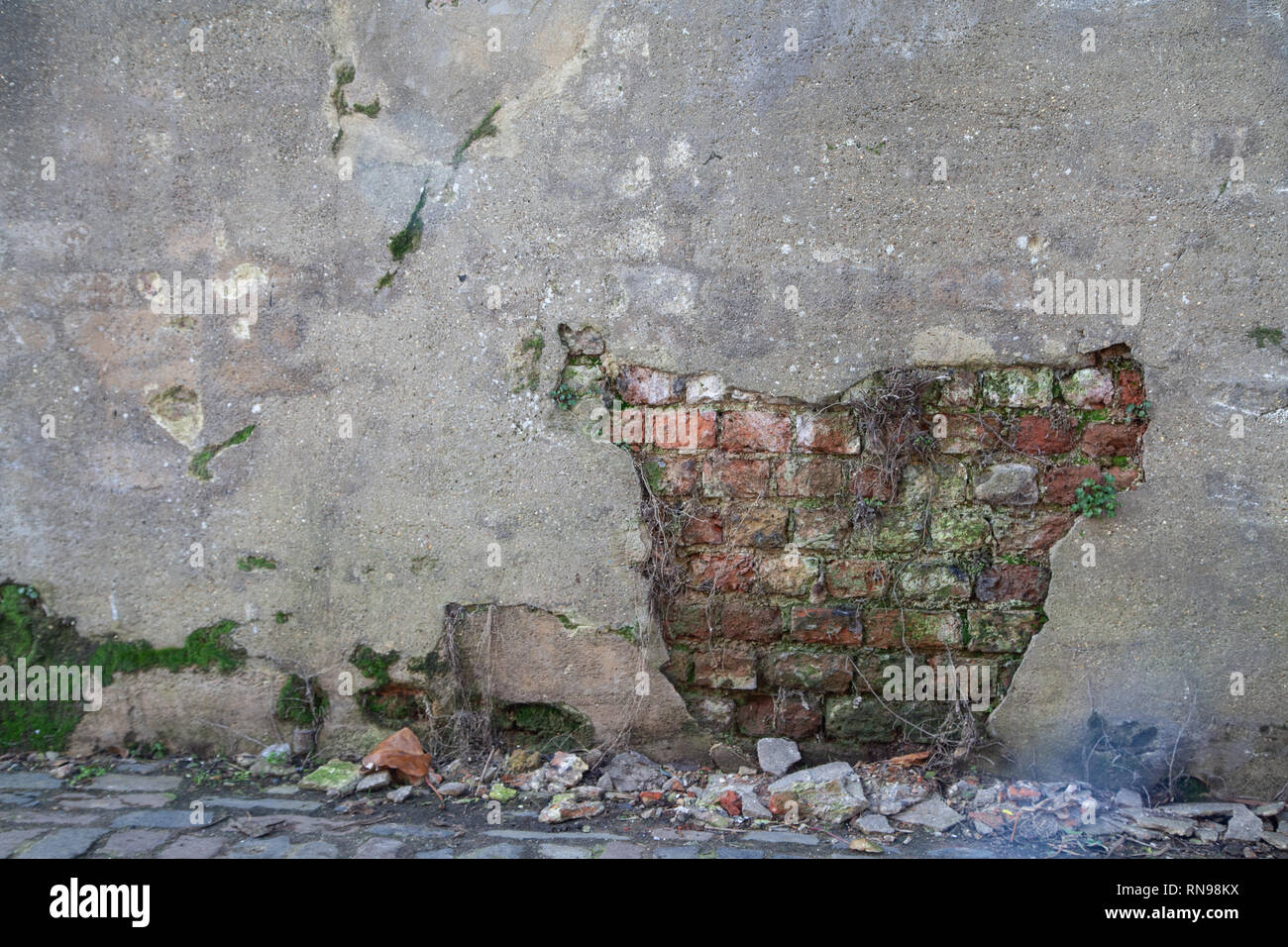 Plaster Missing from Wall Showing Brickwork Underneath Stock Photo