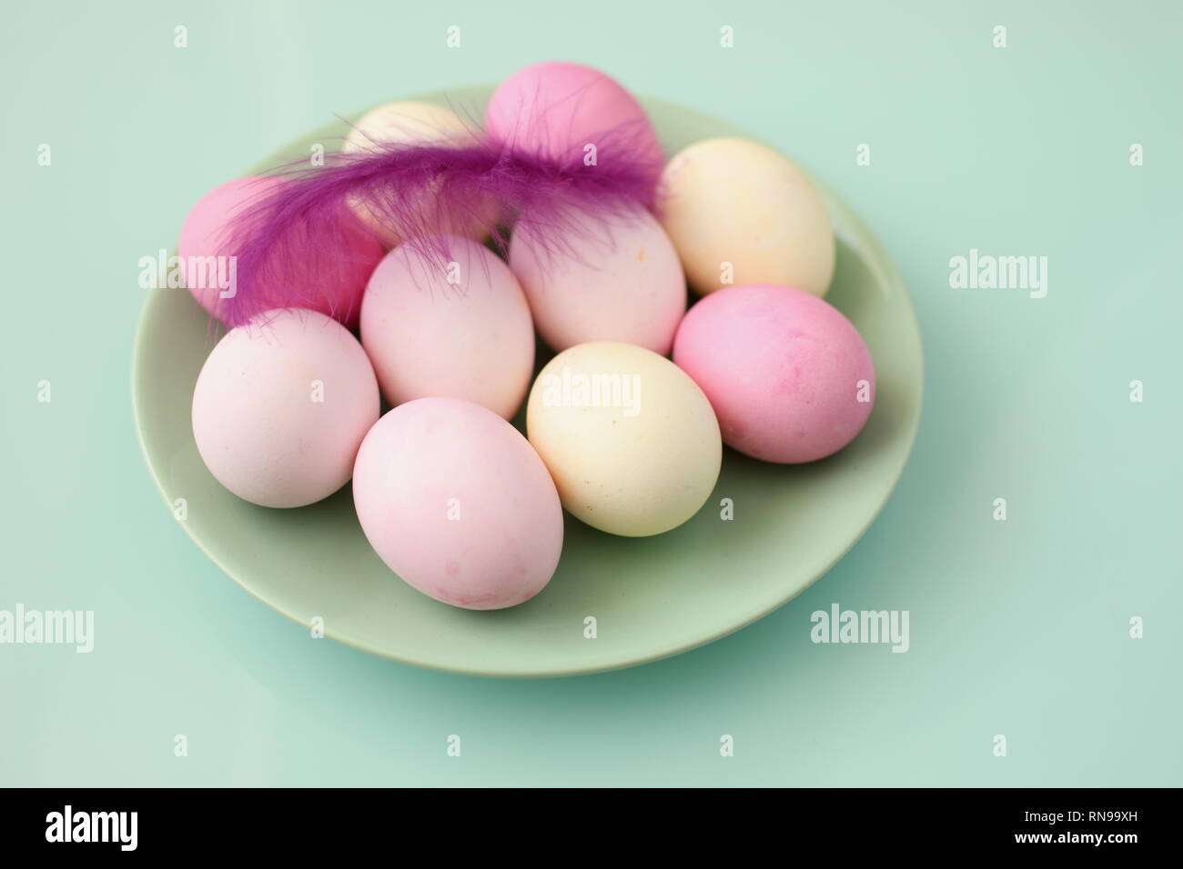 Set of Easter eggs and decorative feather against cyan background Stock Photo