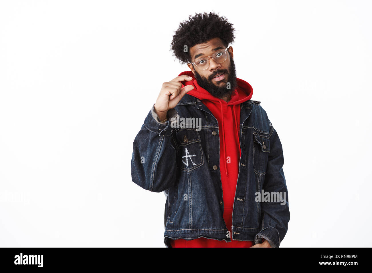 Studio shot of calm and chill good-looking african-american male in  glasses, denim jacket over hoodie shaping small object as giving tiny hint  Stock Photo - Alamy