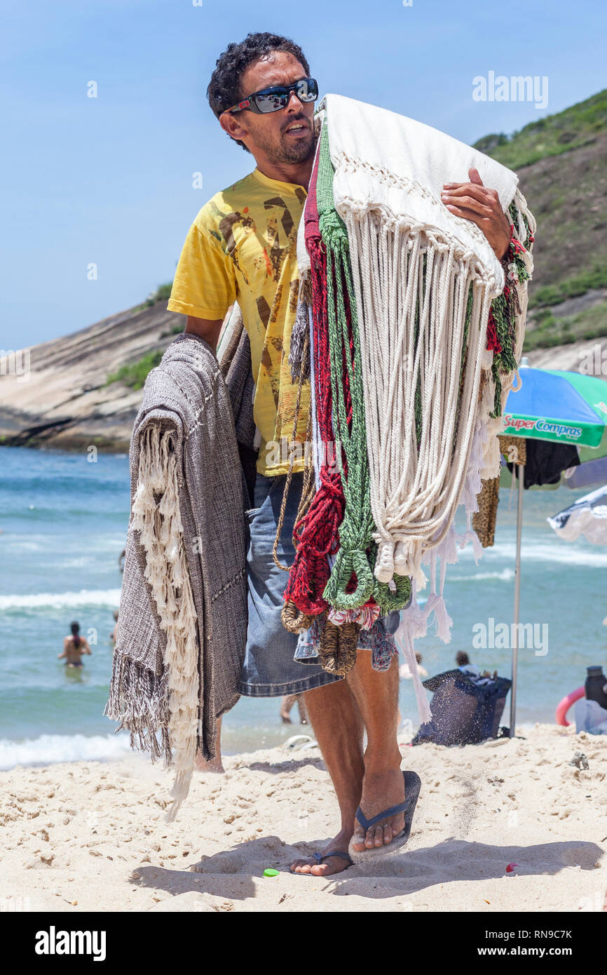 Salesman going around the beach trying to sell hammocks and robes to
