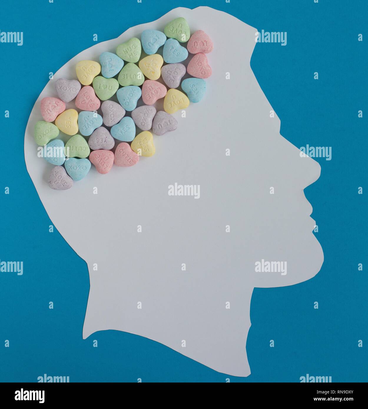 Silhouette of a man's head with candy hearts for a brain. Stock Photo