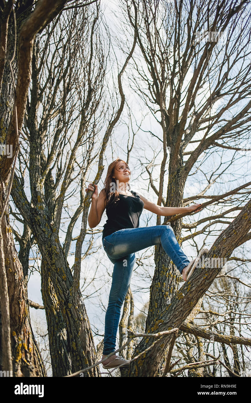 Young girl climbing a tree on a fine spring day. Stock Photo