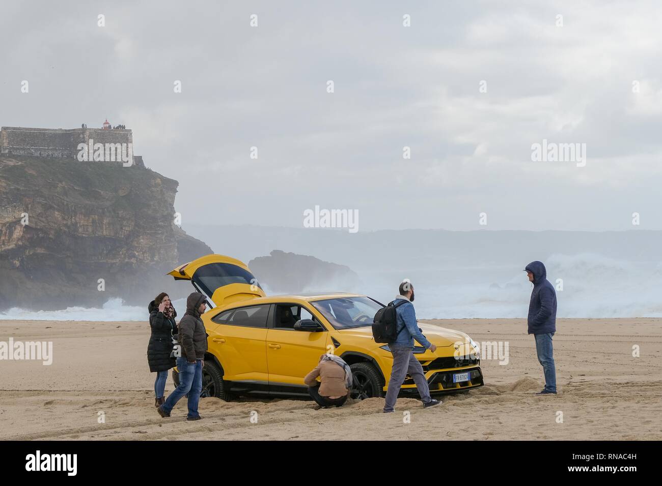 Nazare, Portugal. 18th Feb, 2019. Big wave surfer Alessandro Marciano (accent over 'o') decided to show off his brand new Lamborghini Urus 4x4 on Praia do Norte beach, on the Atlantic coast of Portugal. Alessandro, an Italian surfer spends much of his time in Nazare where the world's biggest waves are to be found. Unfortunately, Bad boy Alessandro appears to have upset the local Police and almost lost his luxury 4x4 to the incoming tide when he managed to get stuck in the soft sand. Credit: Gareth LLewelyn/Alamy Live News Stock Photo