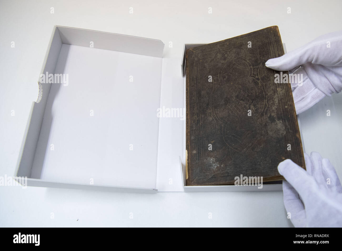 Stuttgart, Germany. 18th Feb, 2019. With gloves, a Bible of the Namibian national hero Hendrik Witbooi is taken from a cardboard box in the Linden Museum. Baden-Württemberg wants to return two stolen colonial goods to Namibia. The Association of Nama Tribal Elders (NTLA) wants to prevent the return. (to dpa 'Nama-representation wants to prevent return of Bible and whip' from 18.02.2019) Credit: Marijan Murat/dpa/Alamy Live News Stock Photo