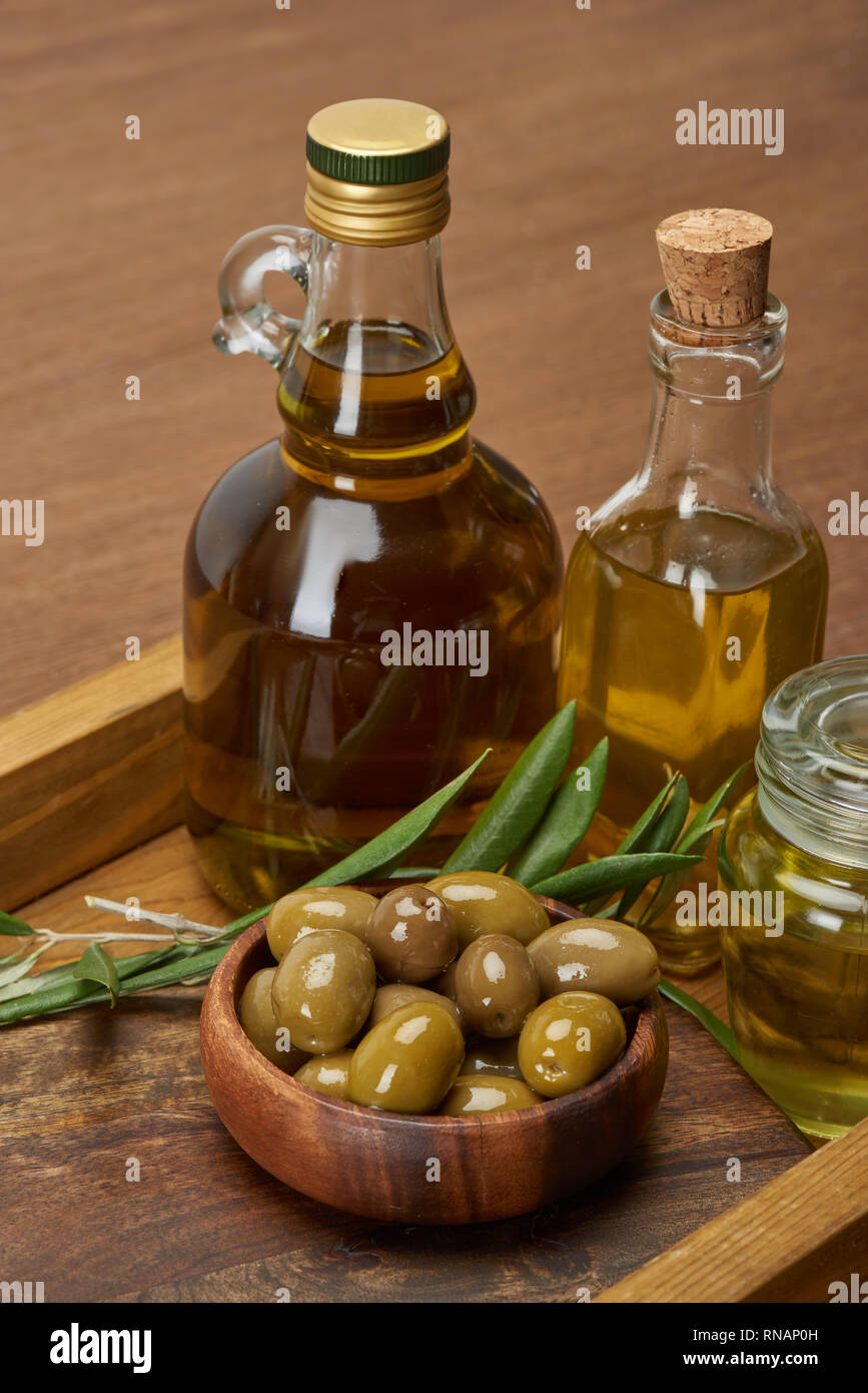 wooden tray with different oil bottles, bowl of olives and olive tree ...