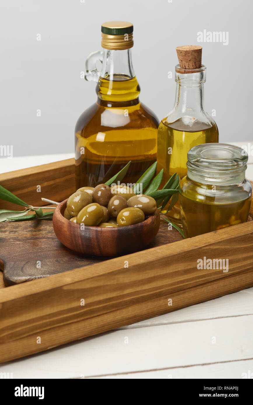 wooden tray with bowl of olives, oil bottles and olive tree leaves on ...